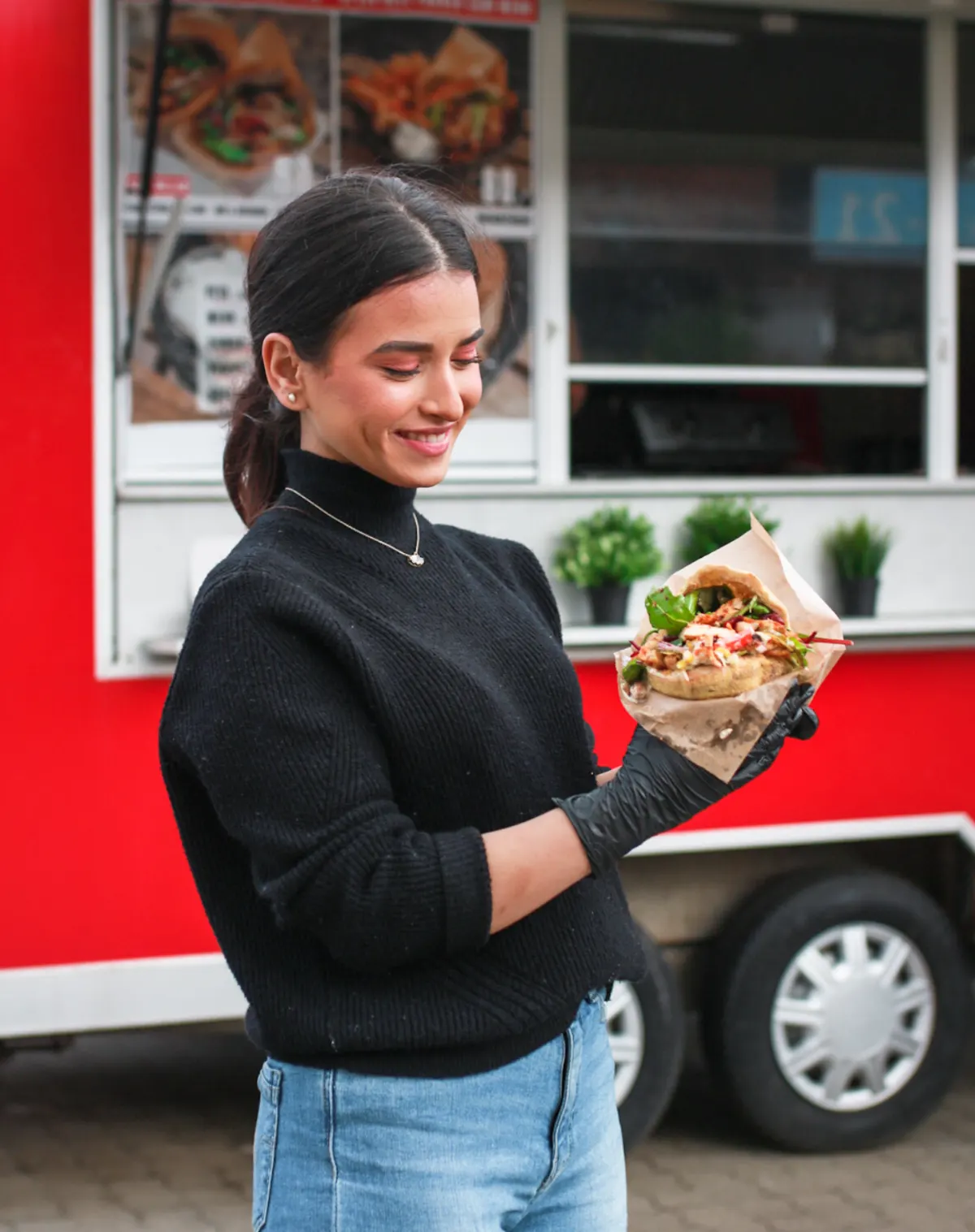 Medarbejder fra Just Pita med en frisk pita foran foodtrucken