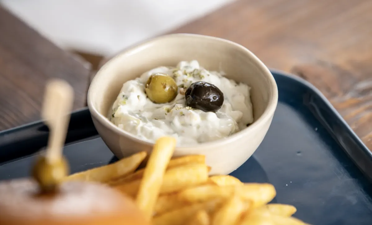 Skål med tzatziki og oliven ved siden af pommes frites